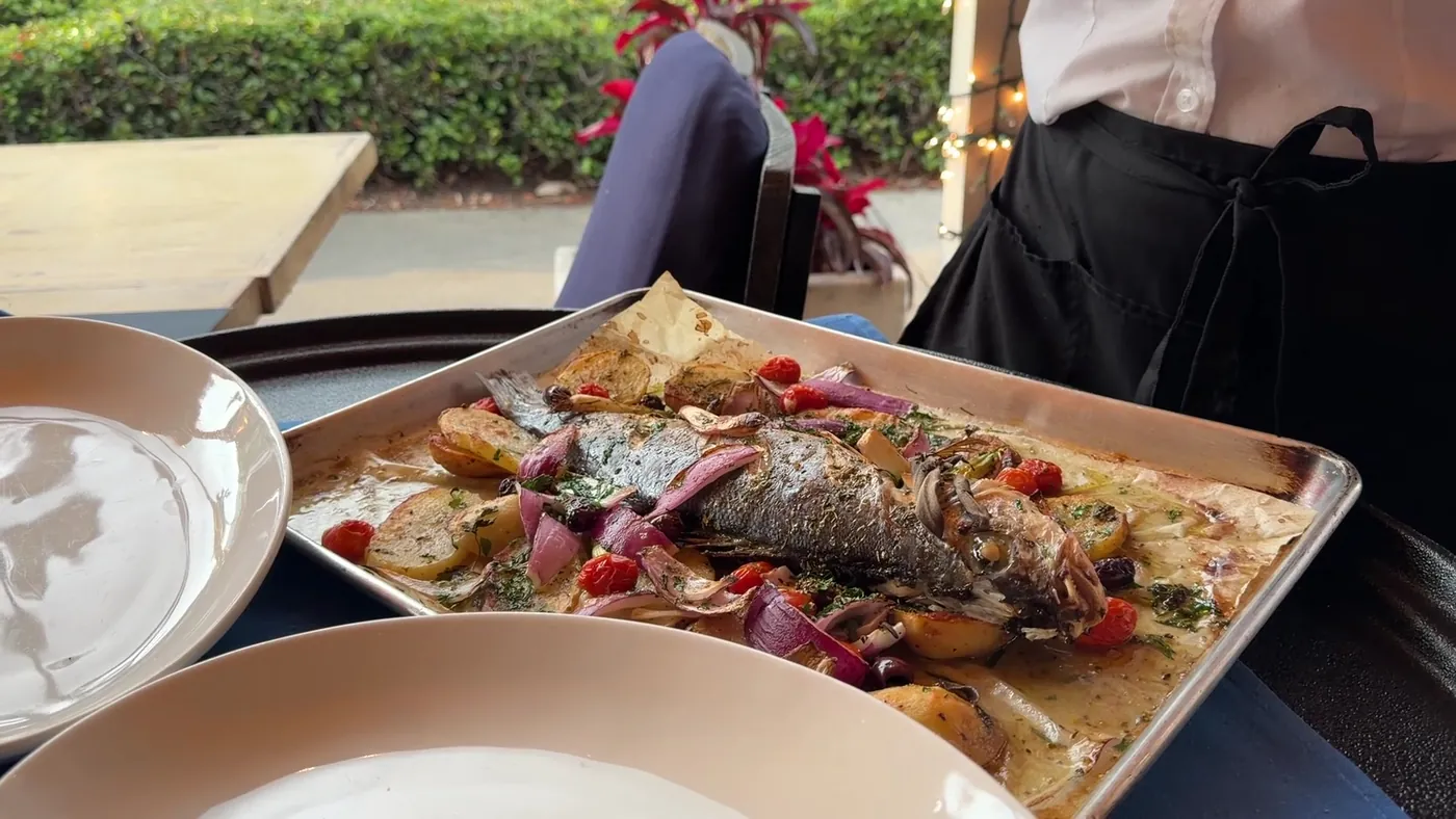 A whole fish baked with cherry tomatoes and olives, ready to be served